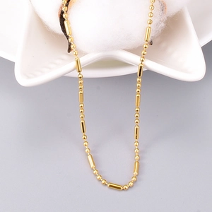 Polished gold-plated stainless steel bead and cylinder chain choker necklace on a star tray