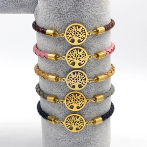 Detail van gevlochten armbanden met gouden Levensboom-hangers in vijf diverse kleuren