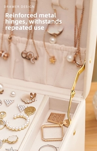 Macro view of reinforced gold-tone hinges and plush interior of the cream jewelry box