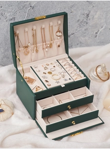 Detailed view of green leather jewelry box with necklace hooks and velvet drawer storage