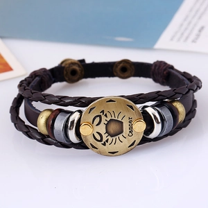 Macro detail of dark brown layered leather bracelet with bronze Cancer zodiac sign charm