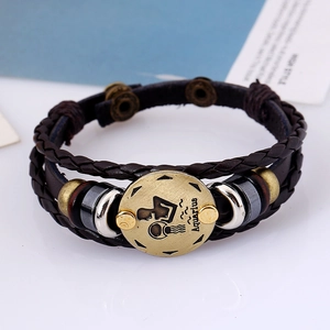 Macro shot of Aquarius sign on braided brown leather bracelet with vintage bronze charms