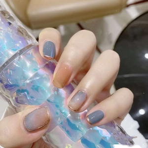 Macro shot of gradient blue and pink press-on nails with elegant gold French tips
