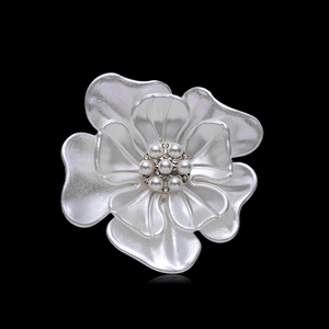 Détail macro de broche camélia avec pétales perlés et centre en zircon sur fond noir