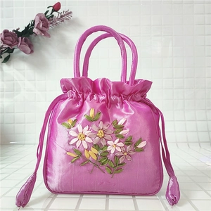 Close-up of magenta silk bucket bag featuring floral embroidery and drawstring closure