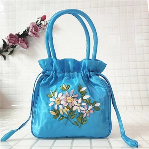 Close-up of royal blue satin handbag with 3D floral ribbon embroidery and drawstring