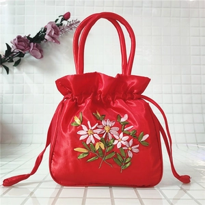 Detail of red satin bucket bag featuring intricate floral ribbon embroidery and drawstring