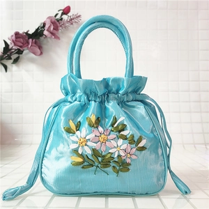 Close-up of light blue satin drawstring handbag with exquisite floral silk ribbon embroidery