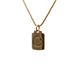 Macro shot of polished gold copper necklace featuring a rectangular letter C pendant