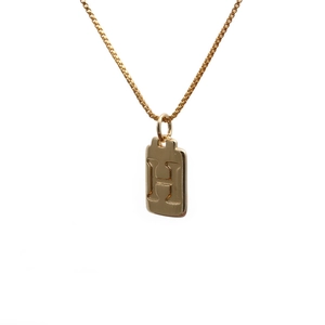 Macro view of a gold-plated square pendant with an H letter on a durable box chain