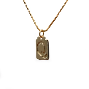 Close-up of a gold square pendant necklace featuring an embossed letter Q on a box chain