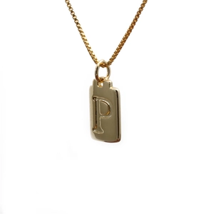 Macro view of gold pendant featuring an engraved capital letter P on a fine box chain
