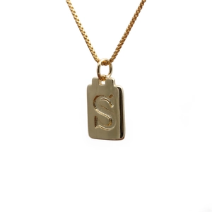 Close-up of gold-plated rectangle pendant with engraved letter S on box chain necklace