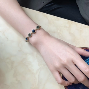 Elegant gold-plated bracelet with navy blue and grey round crystals on marble background