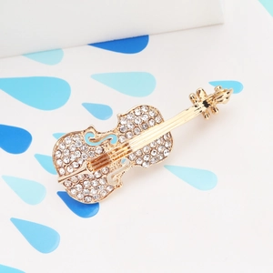Macro shot of violin brooch featuring gold-plated metal base and inlaid white rhinestones