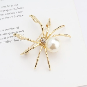 Close-up of gold spider brooch with white faux pearl and crystal rhinestone details