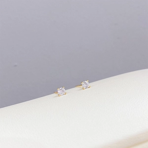 Macro shot of gold-plated stud earrings with sparkling round cubic zirconia in four-prong setting