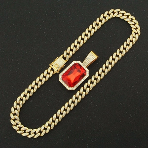 Detailed macro view of a gold Cuban chain necklace with a ruby rectangular pendant