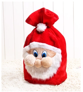 Detail of red velvet Christmas gift bag with a 3D Santa Claus face on wooden background