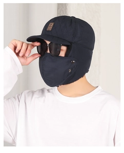 Detail view of navy blue quilted winter hat with earflaps and a detachable face mask
