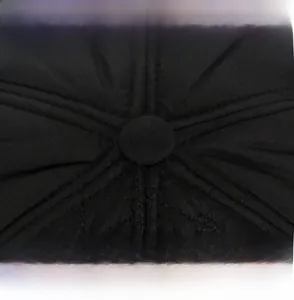 Macro shot of black quilted trapper hat crown with central button and precise stitching