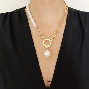 Detail of asymmetric necklace featuring golden paperclip chain and white pearls