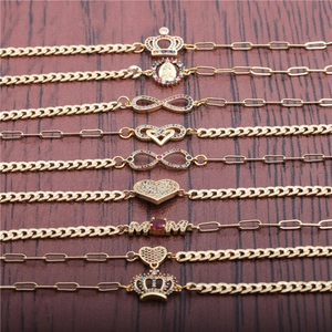 Gold Cuban bracelets set with evil eye and zircon charms on dark wood background