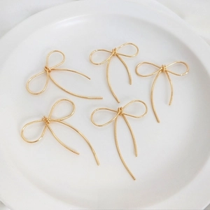 Dettaglio macro di cinque ciondoli a fiocco fatti a mano in oro 14K per creare gioielli