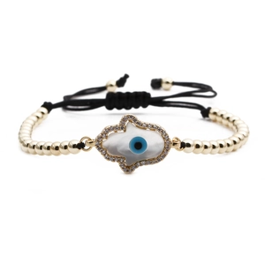 Golden bead chain bracelet with Hamsa hand and blue Evil Eye charm on white backdrop