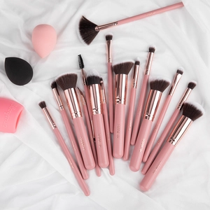 Flat lay of pink makeup brush set with beauty blenders on white silk background