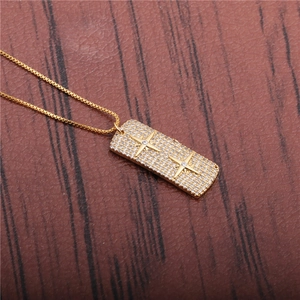 Golden necklace with a zircon-encrusted rectangular planet pendant on wooden surface