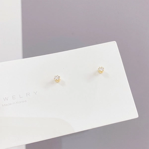 Close-up of minimalist gold cubic zirconia stud earrings set in a prong mounting
