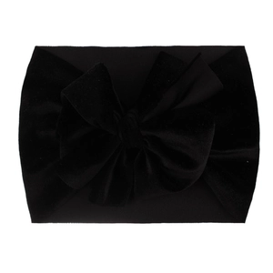 Close-up of soft black velvet baby headband with a large decorative bow on white background