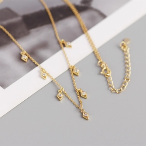 Detail view of gold rhombus pendant necklace with zirconia and lobster clasp closure