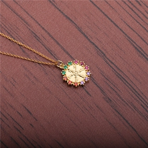 Golden helm pendant necklace with colorful zircons on a dark wood background