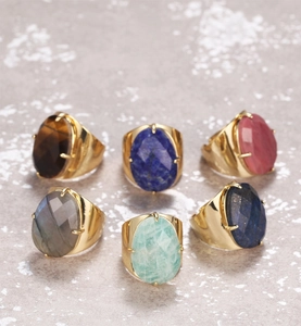 Macro view of adjustable gold-plated rings with various faceted natural gemstones