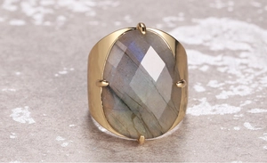 Macro view of faceted oval labradorite gemstone in a vintage gold four-prong setting
