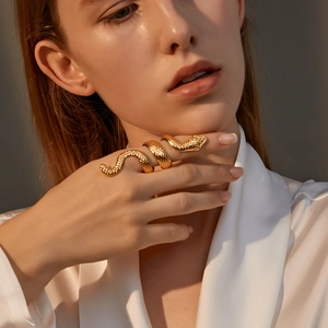 Detailed view of a gold-toned coiled snake ring with realistic scale texture on a finger