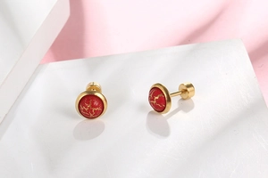 Macro shot of red marble pattern studs with gold trim and secure screw-back design