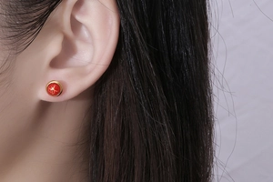 Close-up of red vintage crackle stud earring with gold-rimmed base on ear