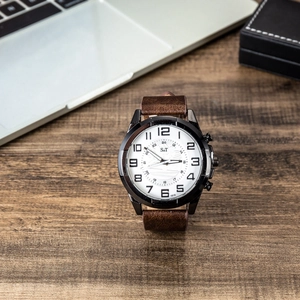 Men's analog watch with brown leather strap and white dial on dark wood background