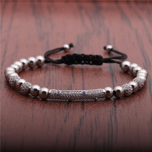 Detail of silver beaded evil eye bracelet with pavé zircon bar on wood surface
