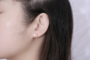 Close-up of cute rainbow cloud stud earrings in gold plating worn by a model