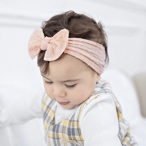 Close-up of pink polka dot baby headband with a large decorative bow and soft nylon band