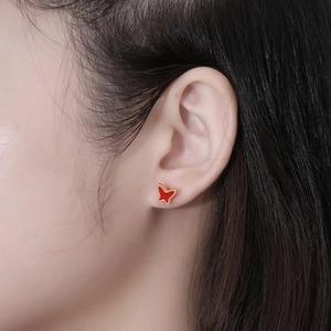 Elegant red butterfly wing stud earrings in titanium steel shown on ear model