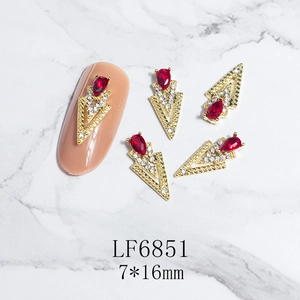 Detail of red teardrop nail gem with gold V-base and 7x16mm sizing on marble background