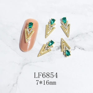 Macro view of 7x16mm golden hollow triangle nail art jewelry with green drop gems