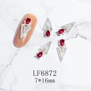 Macro view of 3D V-shaped nail art charms with red teardrop stones and silver settings