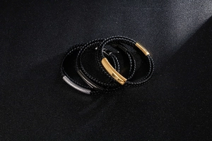 Macro view of men's braided black leather bracelets with gold and silver steel clasps