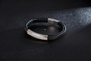 Detail of black woven leather bracelet with polished steel plate and dotted texture